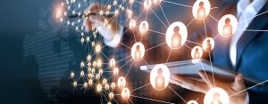 FinTech Partnerships | abstract image of interconnected avatars in foreground, person wearing a business suit and holding a tablet and tablet stylus in background