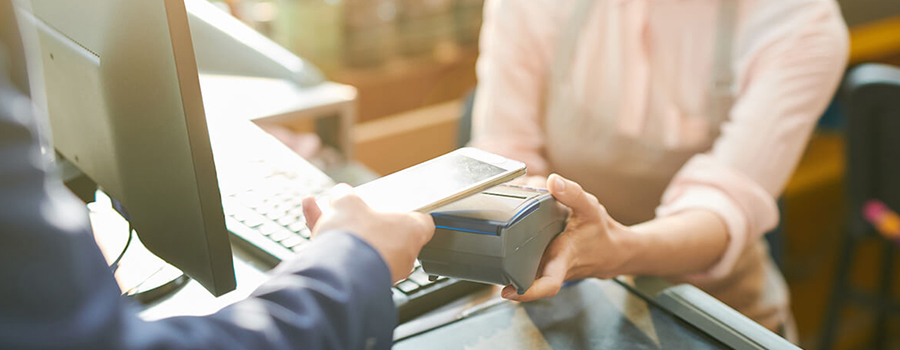 Real Time Payments | image of a person holding a smartphone using tap-to-pay. a second person is in front of them holding the payment processing device