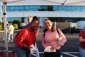 two COCC employees smiling and participating in an outdoor happy hour
